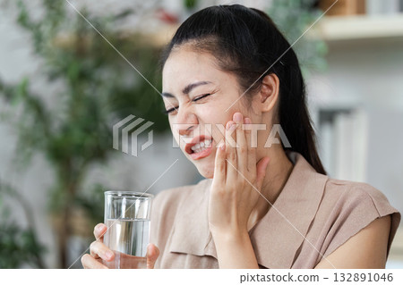 Dental Pain Relief. Woman experiencing toothache while holding a glass of water. Dental Pain Relief. Woman experiencing toothache while holding a glass of water. 132891046