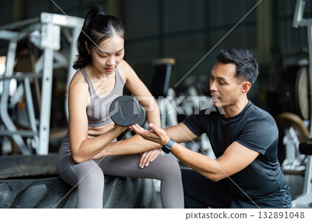 Personal Trainer Guiding Female Client with Dumbbell. Focus on Strength and Fitness. Personal Trainer Guiding Female Client with Dumbbell. Focus on Strength and Fitness. 132891048