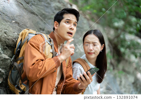 Hiking Discussion. Young man explaining something to his partner while resting on a rocky path. 132891074
