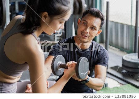 Personal Training. Man coaching woman with dumbbell in gym. 132891080