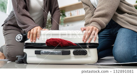 Travel Planning and Packing. Friends closing a suitcase together. 132891081