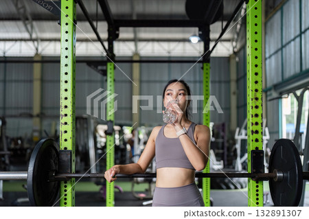 Hydration Focus. Client taking a water break during workout in gym. 132891307