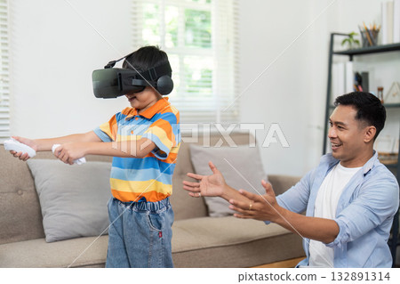 Virtual Reality and Family Interaction. A father watches his son play a VR game at home. Virtual Reality and Family Interaction. A father watches his son play a VR game at home. 132891314