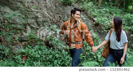 Couple holding hands while hiking through lush greenery 132891462