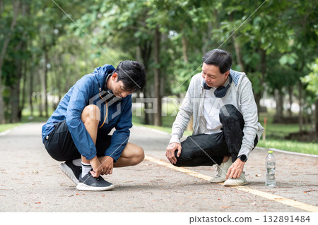 Father and Son Tying Shoelaces. Promoting wellness through supportive activities. Father and Son Tying Shoelaces. Promoting wellness through supportive activities. 132891484