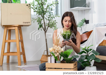 Settling In with Greenery. A woman arranges plants in her new home. 132891523