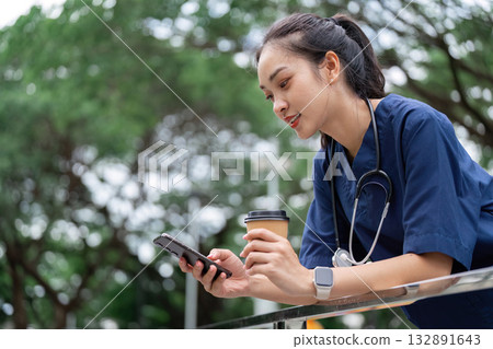 Doctor using smartphone while enjoying coffee outdoors Doctor using smartphone while enjoying coffee outdoors 132891643