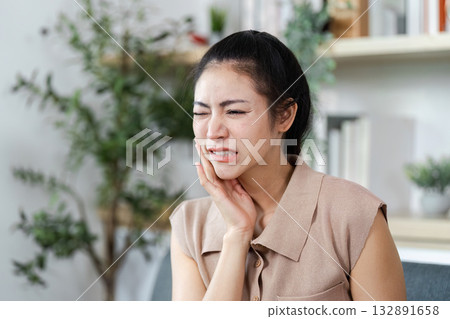 Toothache and Dental Pain. A woman holding her jaw in pain, reflecting common dental issues. 132891658