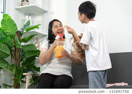 Cleaning and Fun. Mother and son share a laugh while cleaning. Cleaning and Fun. Mother and son share a laugh while cleaning. 132891788