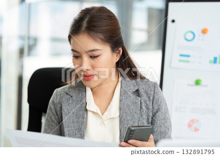 Focused Work and Analysis. Young woman reviewing financial documents in office. 132891795