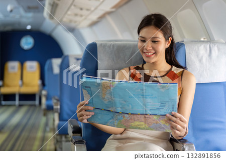 Travel Planning. Young woman reading map on airplane for her next destination. 132891856