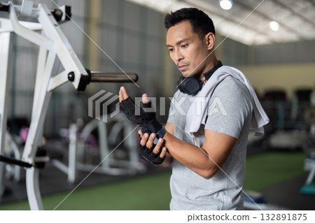 Fitness and Wellness. Young man preparing for workout in gym with headphones. Fitness and Wellness. Young man preparing for workout in gym with headphones. 132891875