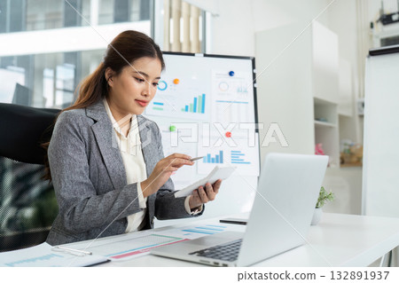 Remote Work and Productivity. Businesswoman analyzing data on tablet in modern office. Remote Work and Productivity. Businesswoman analyzing data on tablet in modern office. 132891937