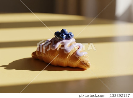 Miniature ceramic croissant with lavender icing and blueberries on a sunny yellow surface Miniature ceramic croissant with lavender icing and blueberries on a sunny yellow surface 132892127