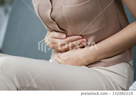 Health and Wellness. Woman experiencing stomach pain, holding her abdomen in discomfort. 132892229