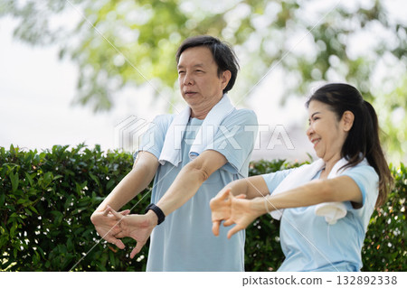 Wellness and Senior Fitness. An elderly couple engaging in stretching exercises outdoors to promote health and well-being. 132892338