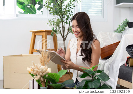 Planning Home Decor. A woman sketches ideas while surrounded by plants. Planning Home Decor. A woman sketches ideas while surrounded by plants. 132892399