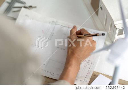 Architect Sketching Detailed Building Plans for Sustainable Project 132892442