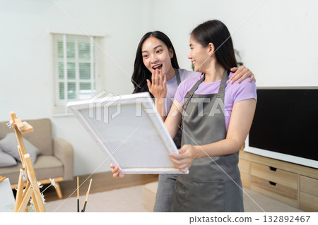 LGBTQIA Couple Sharing Artistic Moments. Two women excitedly presenting their artwork in a bright studio. 132892467