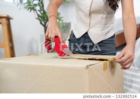 Moving Home: Woman Sealing Box with Tape Moving Home: Woman Sealing Box with Tape 132892514