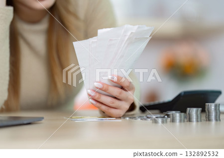 Financial Stress and Budgeting. Woman reviewing bills and receipts at home with concern. Financial Stress and Budgeting. Woman reviewing bills and receipts at home with concern. 132892532