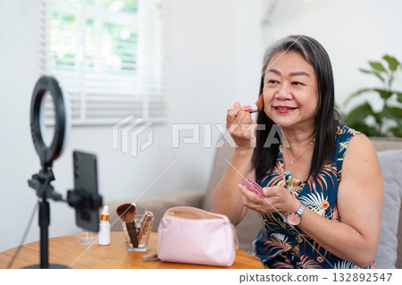 Makeup Application and Joy. A woman applying blush while smiling at her reflection. Makeup Application and Joy. A woman applying blush while smiling at her reflection. 132892547
