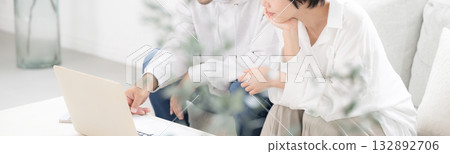 A couple looking at a computer in the living room, thinking seriously, worrying, and wondering. Search and find. Banner for moving, insurance, etc. A couple looking at a computer in the living room, thinking seriously, worrying, and wondering. Search and find. Banner for moving, insurance, etc. 132892706