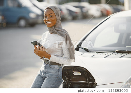Islam black girl charging electro car. Eco car. Islam black girl charging electro car. Eco car. 132893093