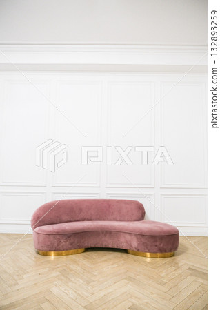 A pink couch is sitting in front of a white wall 132893259