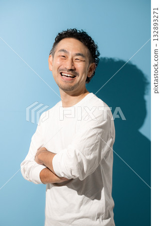 A middle-aged man with a refreshing beard, arms crossed, looking at the camera against a light blue background 132893271