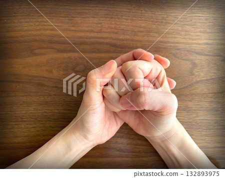 A woman's hand clenching her fist on a desk A woman's hand clenching her fist on a desk 132893975