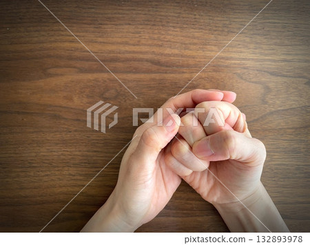 A woman's hand clenching her fist on a desk 132893978