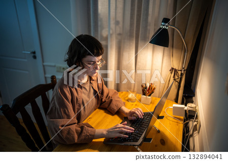 Young business woman freelancer working late at night on laptop, finishing projects, typing reports. Young business woman freelancer working late at night on laptop, finishing projects, typing reports. 132894041