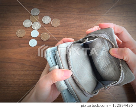 A woman's hand opening an empty wallet and coins on a table A woman's hand opening an empty wallet and coins on a table 132894450