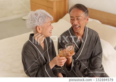 Senior couple having a drink in the bedroom (alcohol, drinking) 132894579