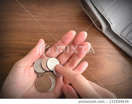 Woman's hands counting coins and a wallet on a desk 132894636