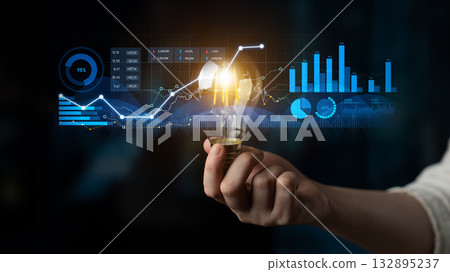 Human Hand Holding Light Bulb Against Digital Graphs and Data Visualizations Representing Innovation and Technology in Business Environment Scalp 132895237