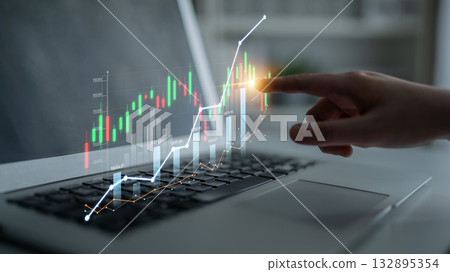 Hand pointing at digital financial graph on laptop screen showing upward trend with colorful candlestick chart in modern workspace with bright light Scalp 132895354