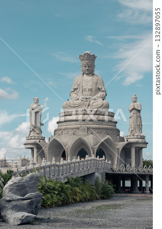A large white marble statue of Guanyin of the Goddess of Mercy. It is seated on a celestial platform. 132897055