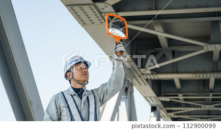 一名工人正在用鏡子檢查橋樑。 132900099