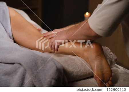 Professional massage taking place in a calm spa environment with soft lighting and relaxing ambiance for therapeutic relief and stress reduction 132900210