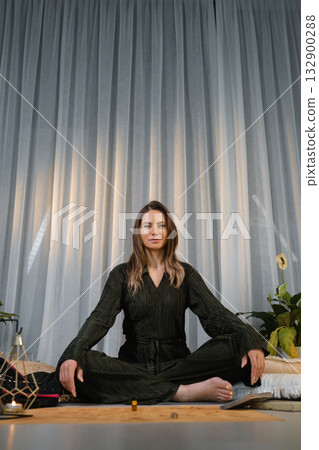 Meditation session in a calm indoor space with plants and soft lighting creating a serene atmosphere for mindfulness practice 132900288
