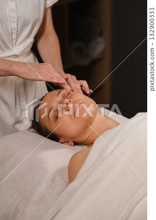Relaxing facial treatment in a serene spa setting with a calm woman enjoying pampering session 132900331