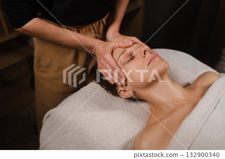 Relaxing massage therapy session in a calm spa setting with a focused therapist and a serene client enjoying the treatment 132900340