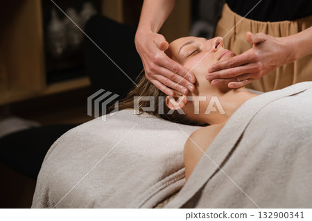 Relaxing facial massage at a spa with a calm atmosphere and soothing lighting, promoting wellness and rejuvenation in a tranquil setting Relaxing facial massage at a spa with a calm atmosphere and soothing lighting, promoting wellness and rejuvenation in a tranquil setting 132900341