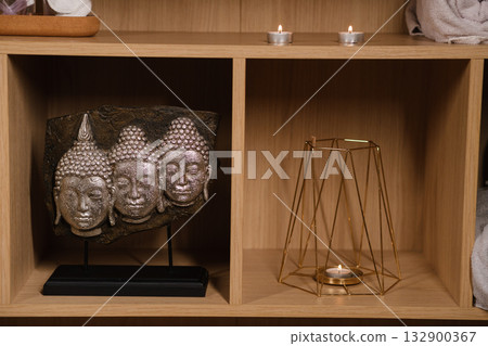 Buddha sculptures and candles create a serene atmosphere in a cozy interior setting for relaxation and mindfulness practice Buddha sculptures and candles create a serene atmosphere in a cozy interior setting for relaxation and mindfulness practice 132900367