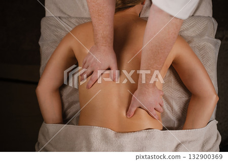 Relaxing session of therapeutic massage in a serene spa environment with a skilled therapist focusing on back muscles 132900369
