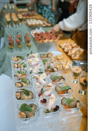 Elegant buffet display featuring a variety of gourmet appetizers at a gathering in a stylish venue Elegant buffet display featuring a variety of gourmet appetizers at a gathering in a stylish venue 132900426