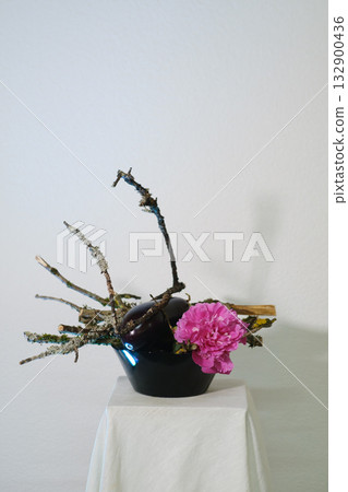 Creative floral arrangement featuring pink flowers and natural branches placed on a neutral background in a simple setting Creative floral arrangement featuring pink flowers and natural branches placed on a neutral background in a simple setting 132900436