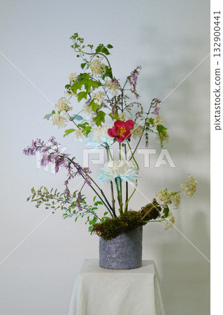 Beautiful floral arrangement featuring colorful blooms and greenery displayed on a pedestal in a bright indoor setting 132900441